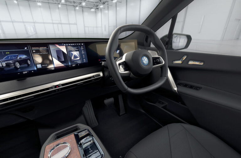 BMW virtual tour - crop taken from the virtual tour of the interior of the BMW iX. The images shows the inside of the iX, which is inside a studio. The dashboard and section of drivers seat can be seen as well as the views through the windscreen and driver's window.